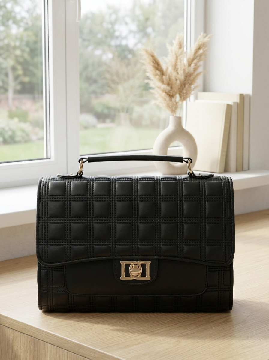 Black quilted handbag on a wooden surface with a window and decorative items in the background