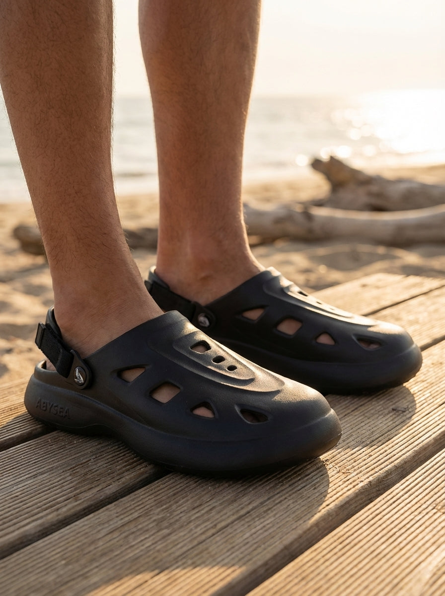 Black sandals worn on a wooden deck with a blurred natural background