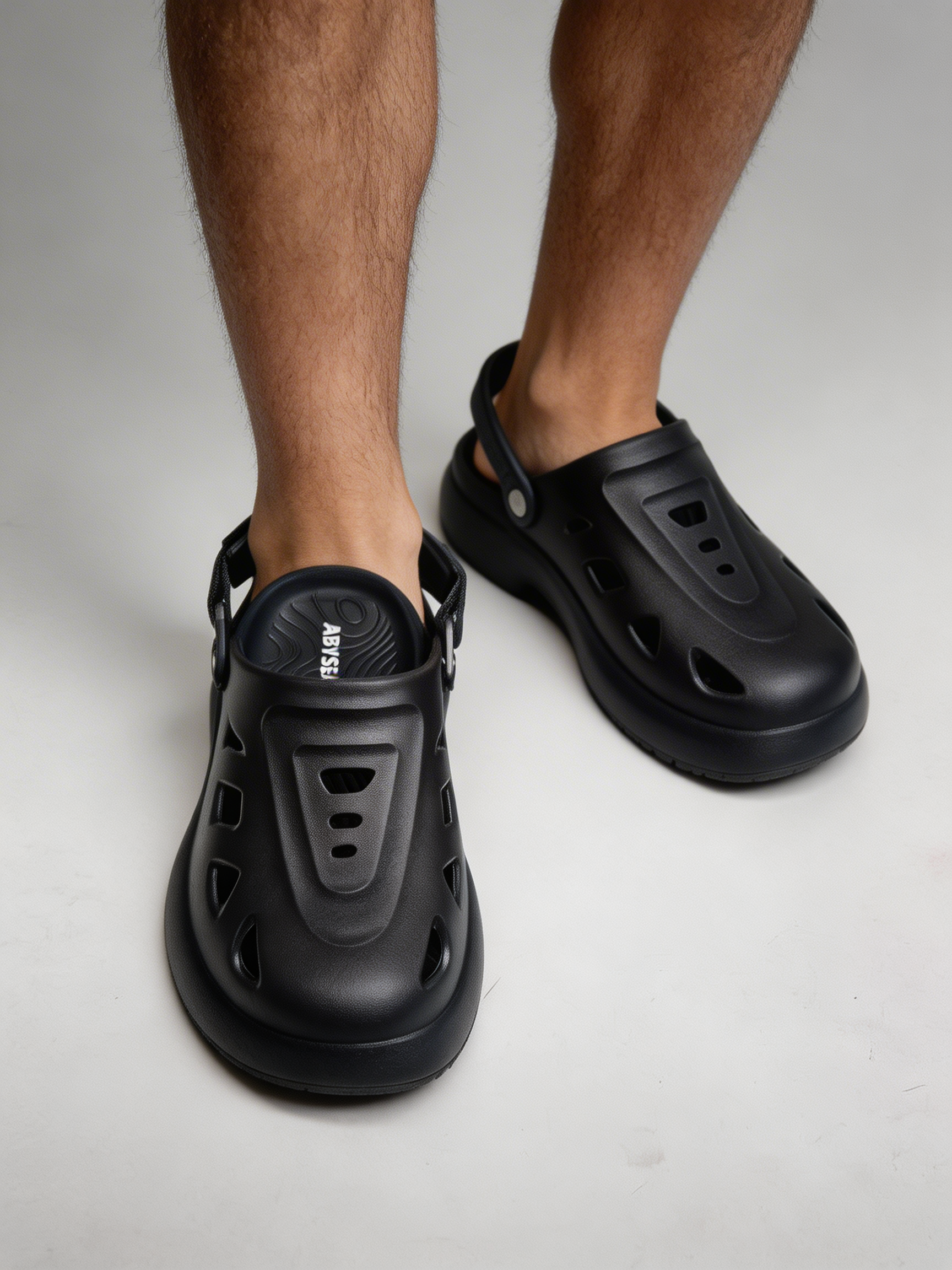 Black clog shoes worn by a person on a light gray background