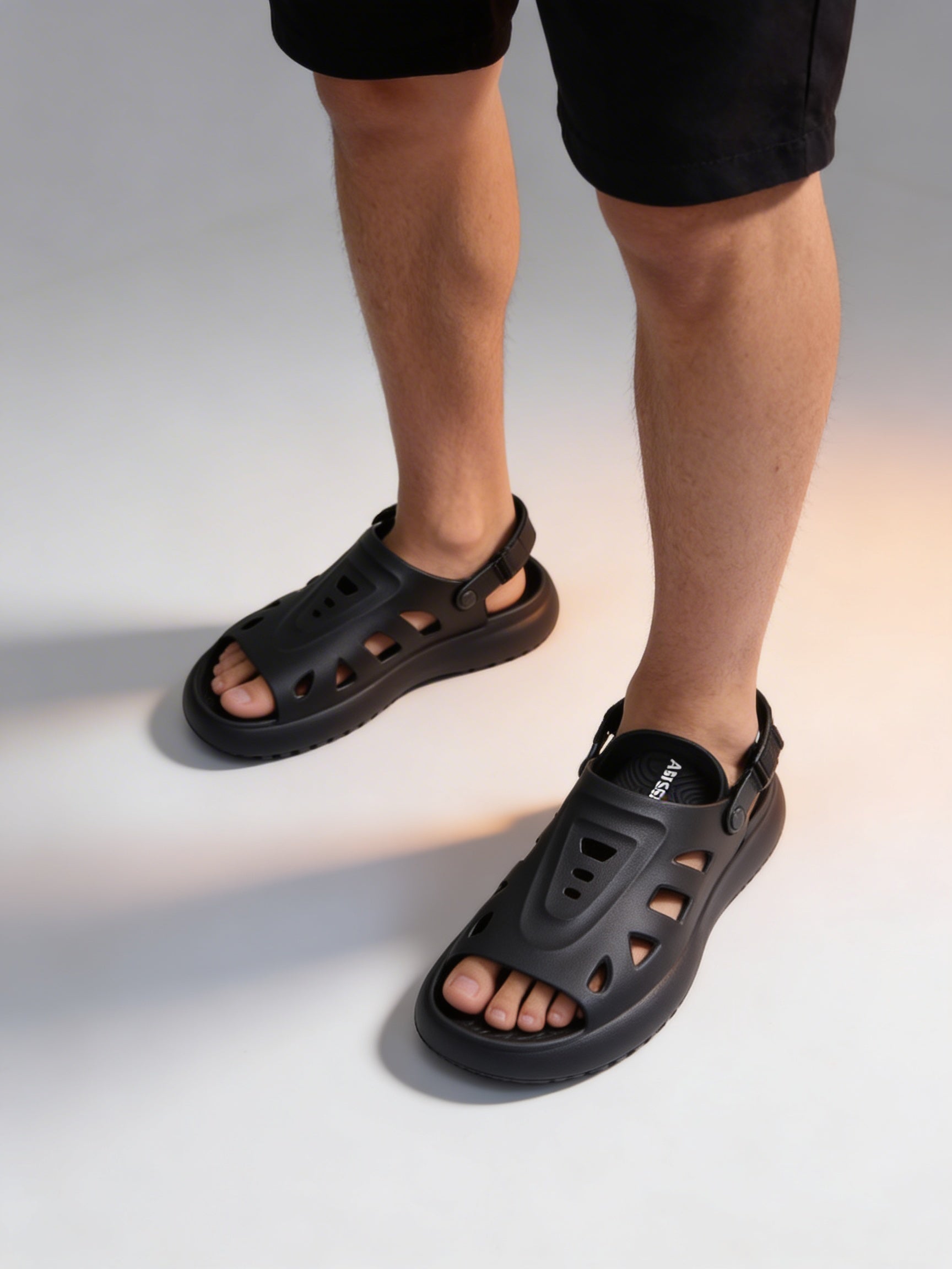 Black sandals worn by a person on a light gray background
