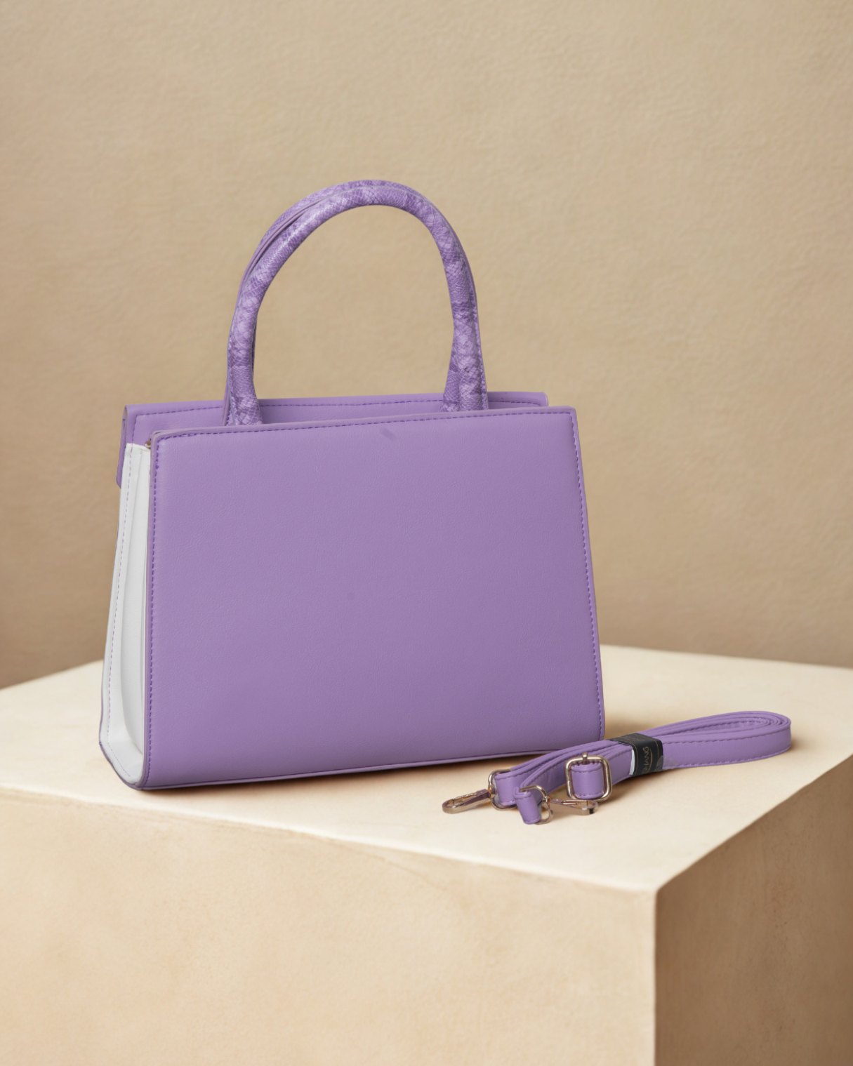 Purple handbag with a matching keychain on a beige surface and background