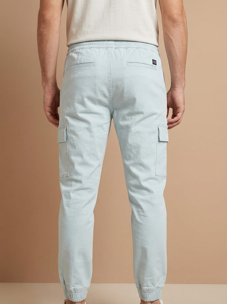 Light blue cargo jogger pants worn by a person on a beige background