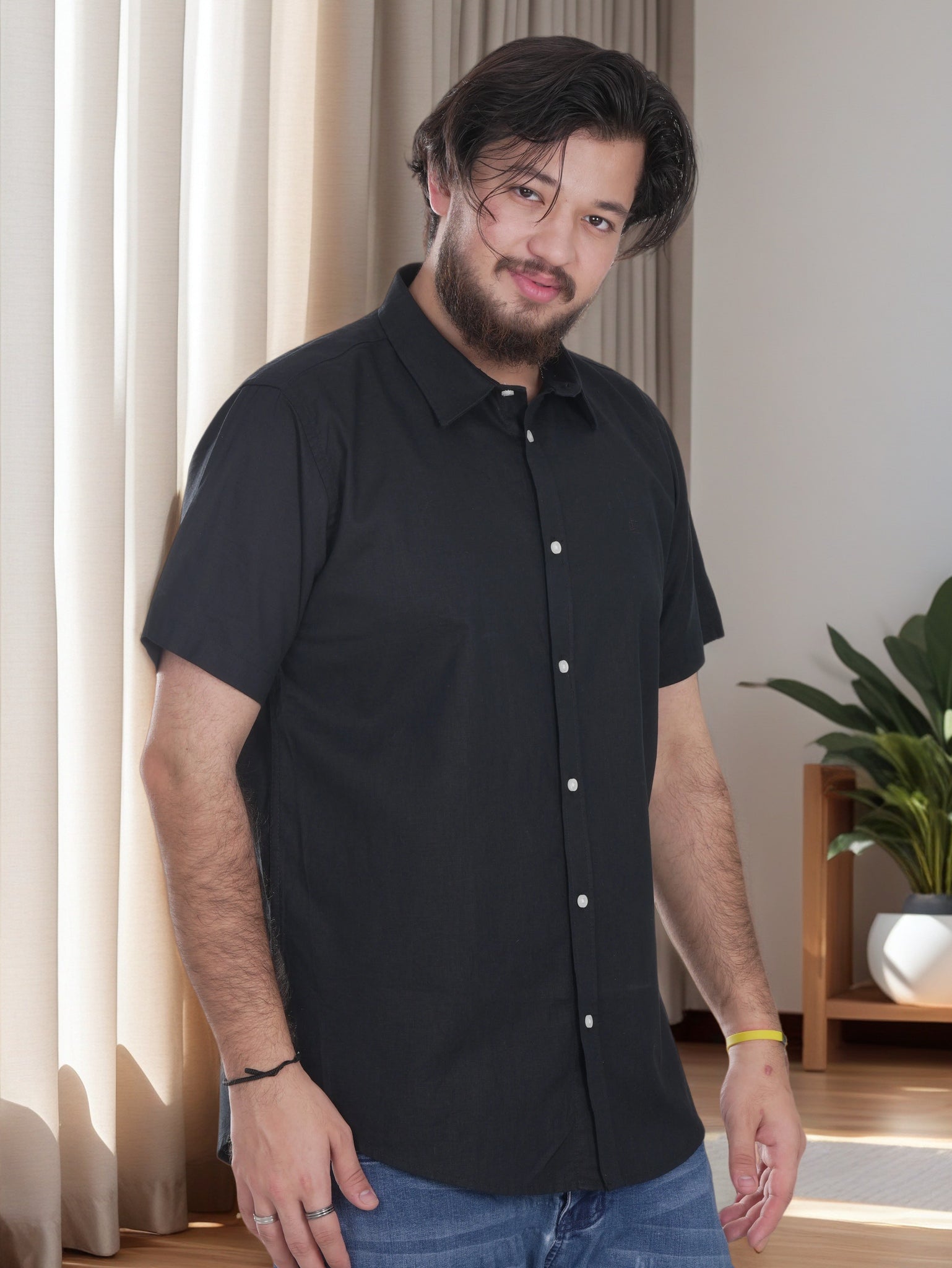 Man wearing a black short-sleeve shirt indoors with a neutral background