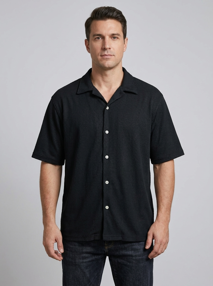 Man wearing a black short-sleeve shirt with buttons on a gray background