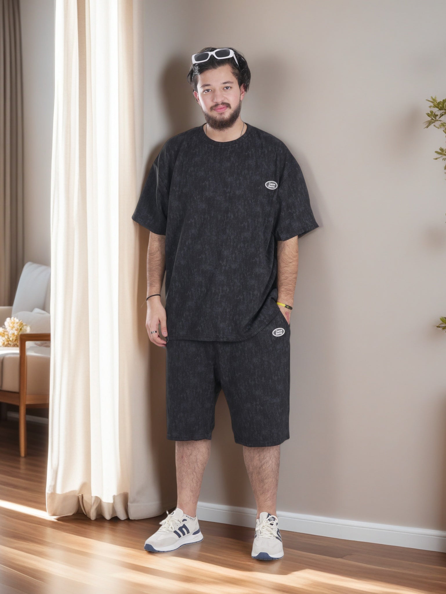 Man wearing a black t-shirt and shorts set with white sneakers in a room.