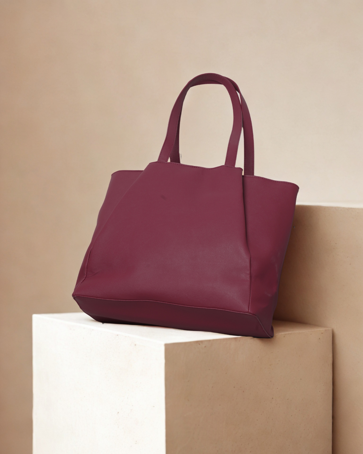 Maroon tote bag on a beige surface with a neutral background