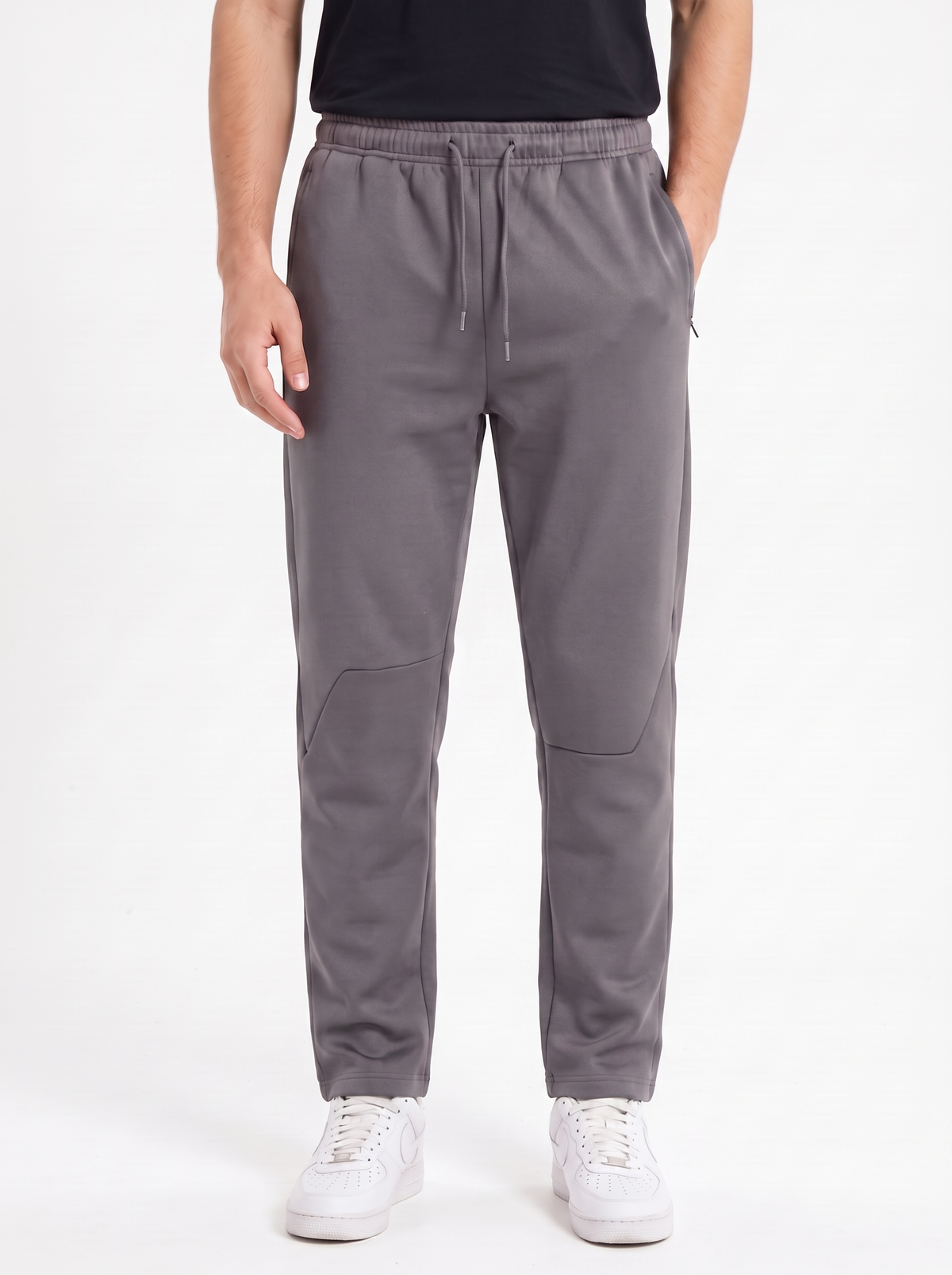 A person wearing gray drawstring jogger-style pants with side pockets and elastic cuffs, paired with a black top and white sneakers, photographed against a plain light background.