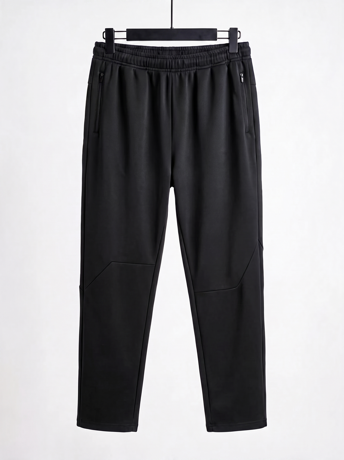 Black slim-fit pants with an elastic waistband, zippered side pockets, and angled seam details on the lower legs, shown hanging against a plain white background.