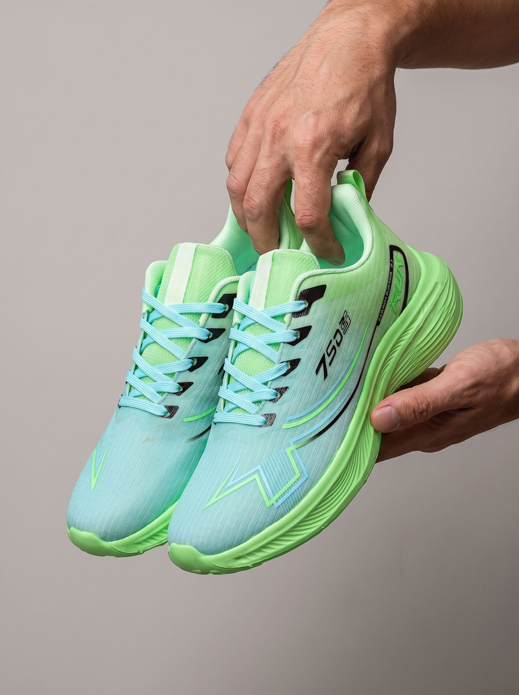A pair of light blue and neon green running shoes held up by two hands against a solid gray background. The shoes feature a textured mesh upper, light blue laces, and a thick, cushioned neon green sole.