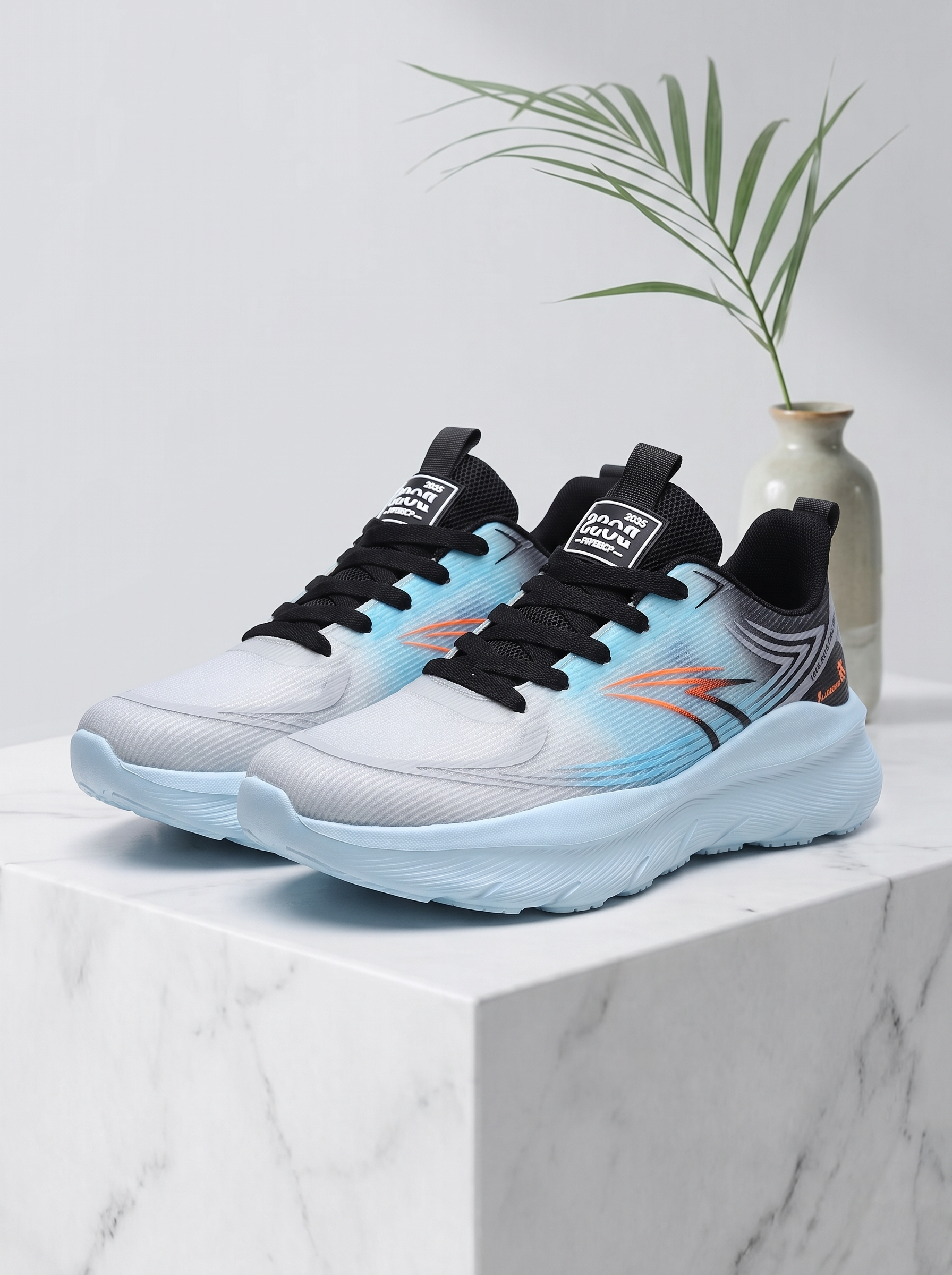 A pair of athletic sneakers with a light gray and white mesh upper, black laces and collar, and a light blue and orange gradient midsole, displayed on a white marble block with a small vase and green plant in the background.