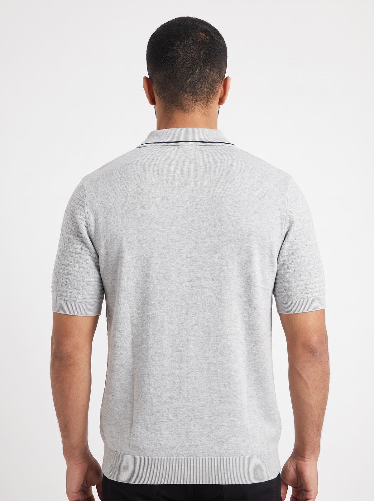 A man viewed from the back wearing a light gray short-sleeve knit polo shirt with a textured pattern on the sleeves and collar, set against a plain white studio background.