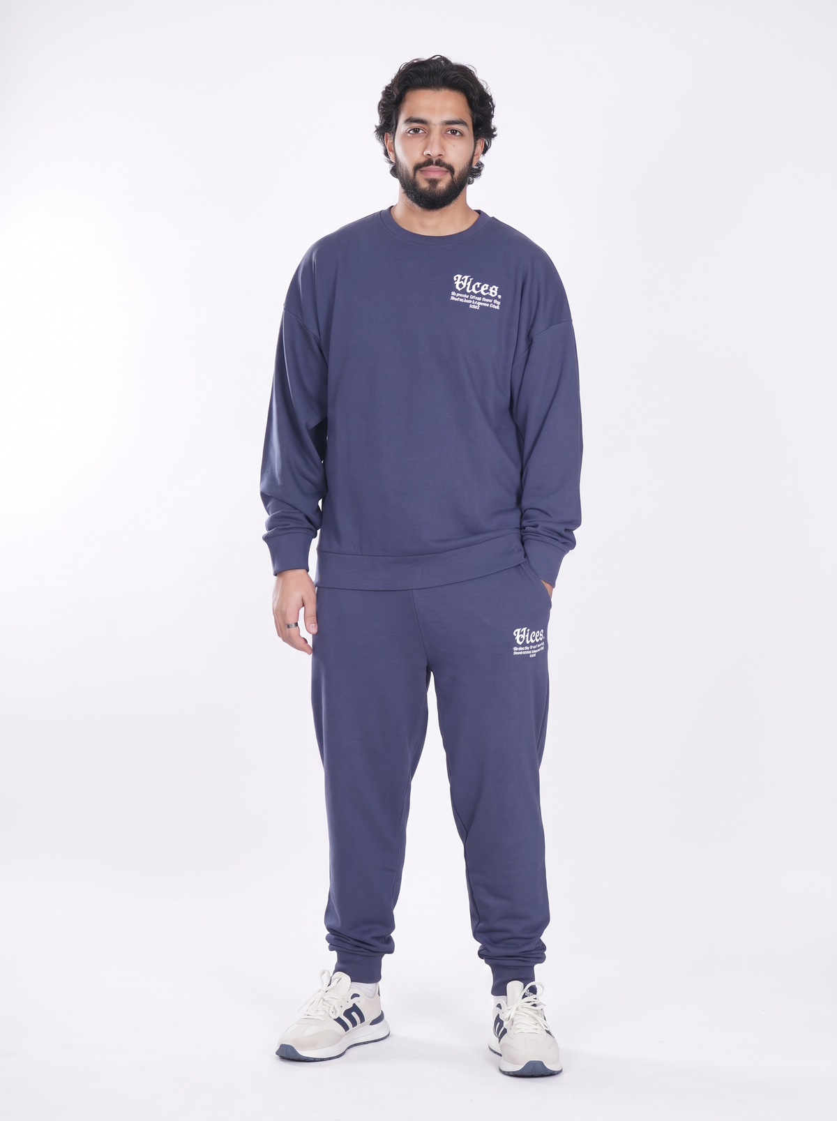 A man modeling a matching navy blue sweatshirt and jogger pants set with white 'Wices' brand graphics, standing against a plain white studio background.