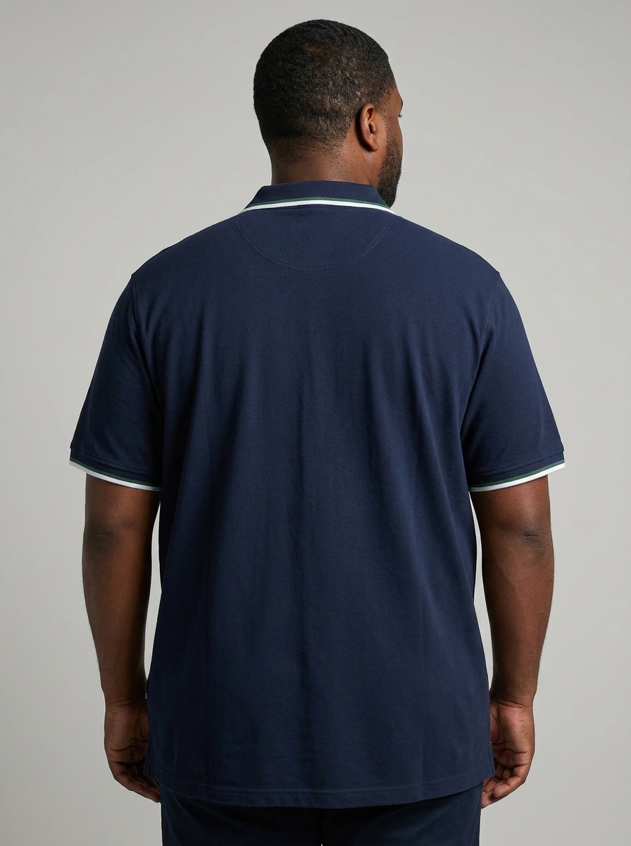 Man wearing a navy blue polo shirt with white trim on a gray background