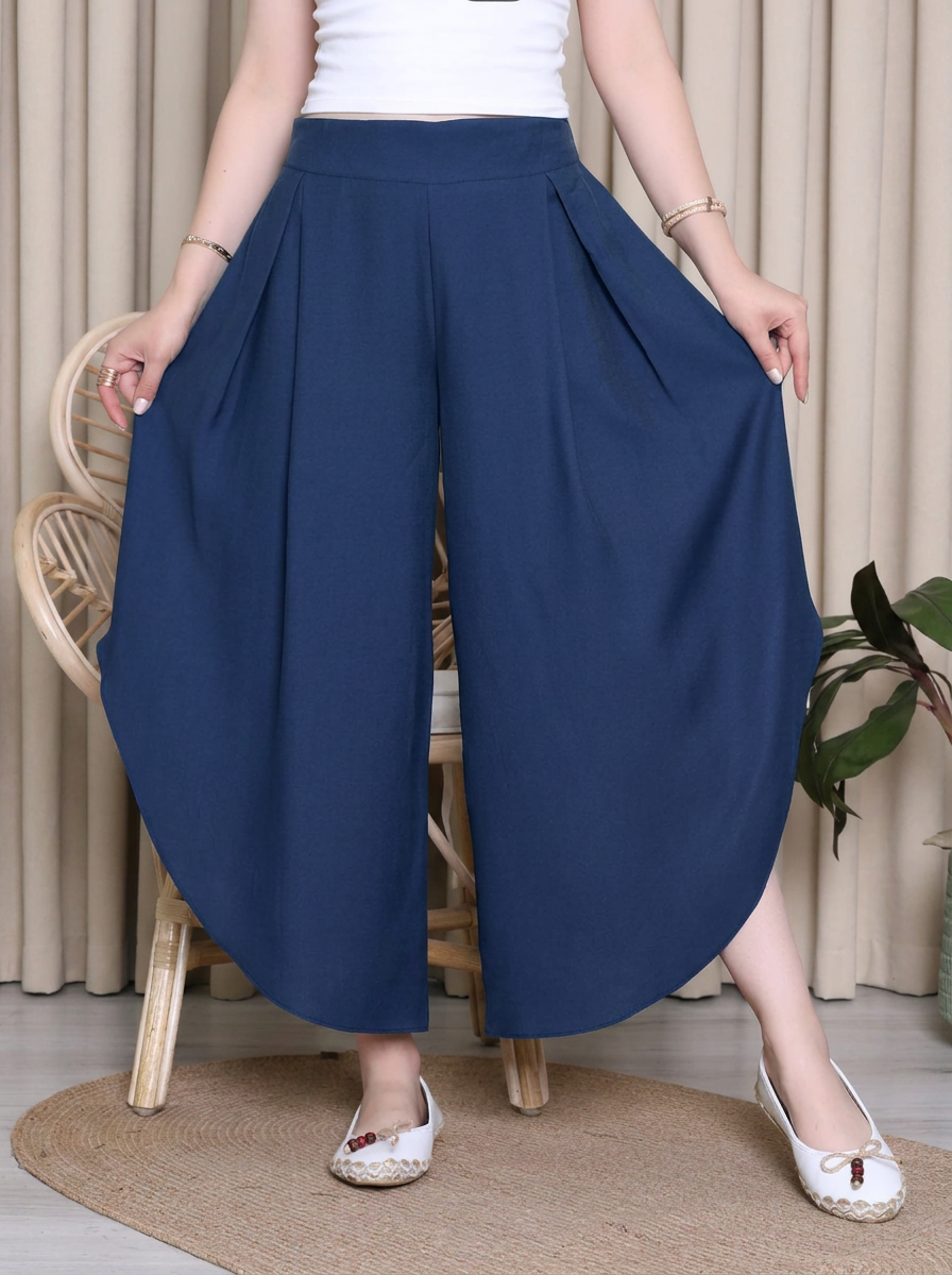 Person wearing blue wide-leg pants and a white top indoors.