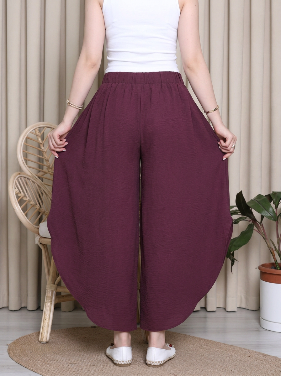 Person wearing maroon wide-leg pants and a white top indoors.