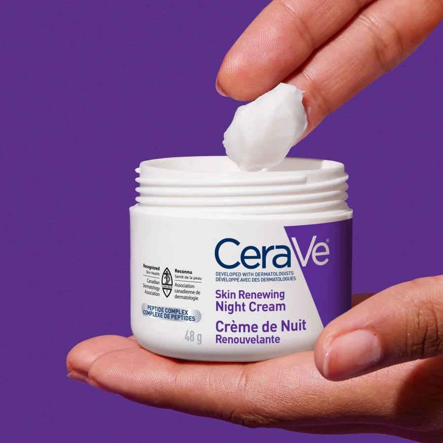 CeraVe Skin Renewing Night Cream being applied with a hand against a purple background