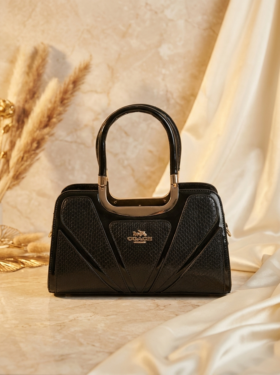 Black handbag with gold handle on a beige fabric background