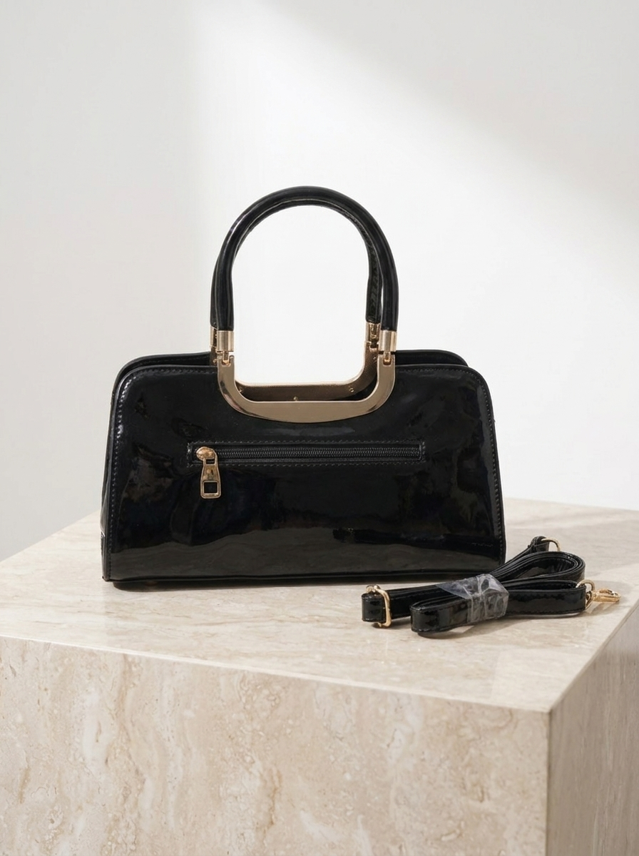 Black handbag with gold accents on a light marble surface