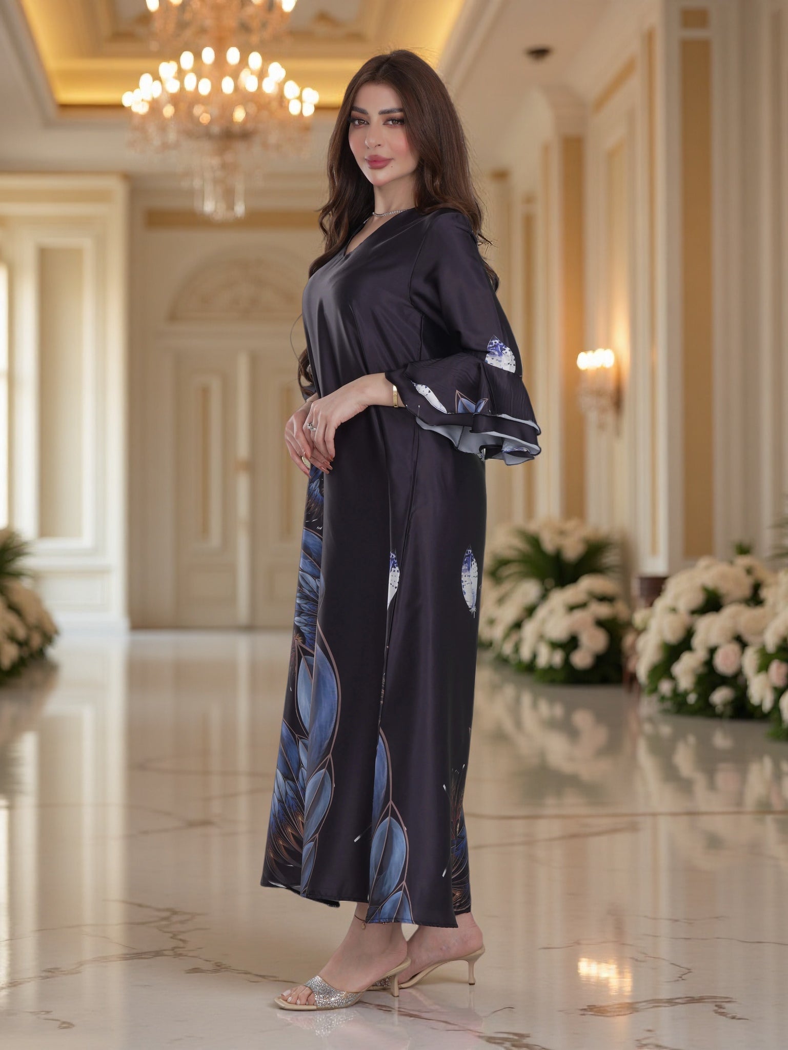 Woman in a black outfit with floral patterns standing in an elegant interior setting.