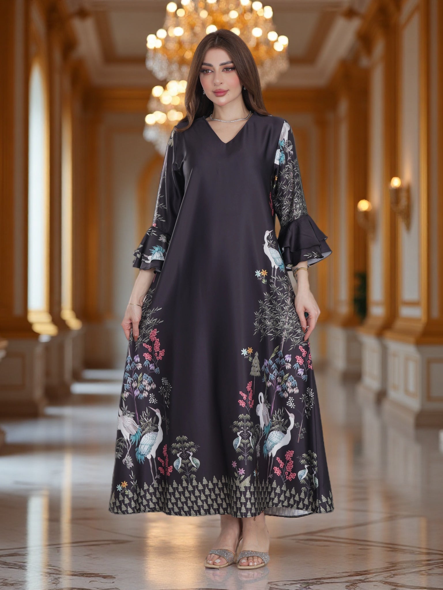 Woman wearing a dark dress with floral and bird patterns in an elegant hallway.