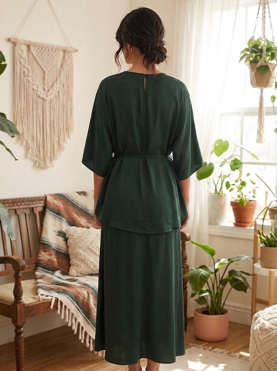 Person wearing a green dress standing in a room with plants and decor.