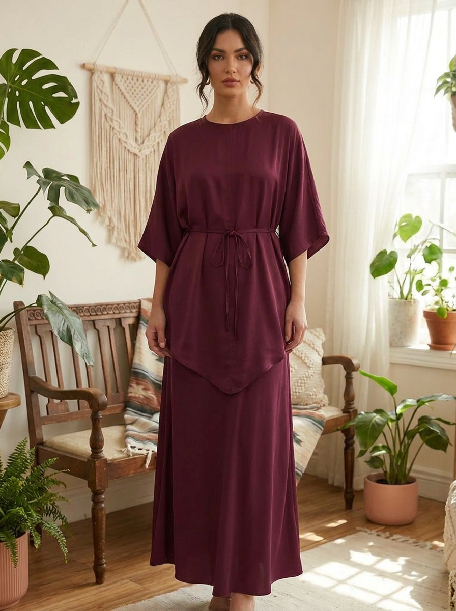 Woman wearing a burgundy dress in a room with plants and wooden furniture