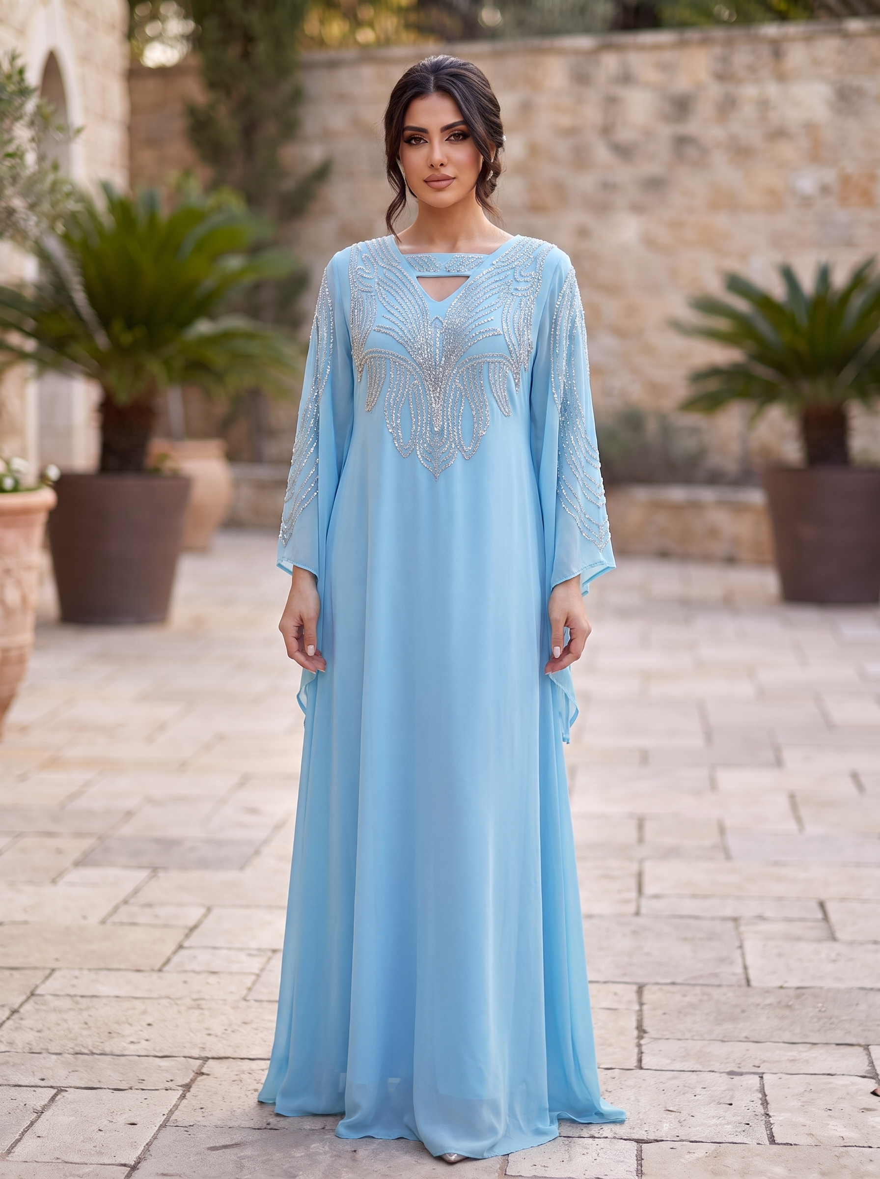 Woman wearing a light blue dress with intricate detailing in an outdoor setting.