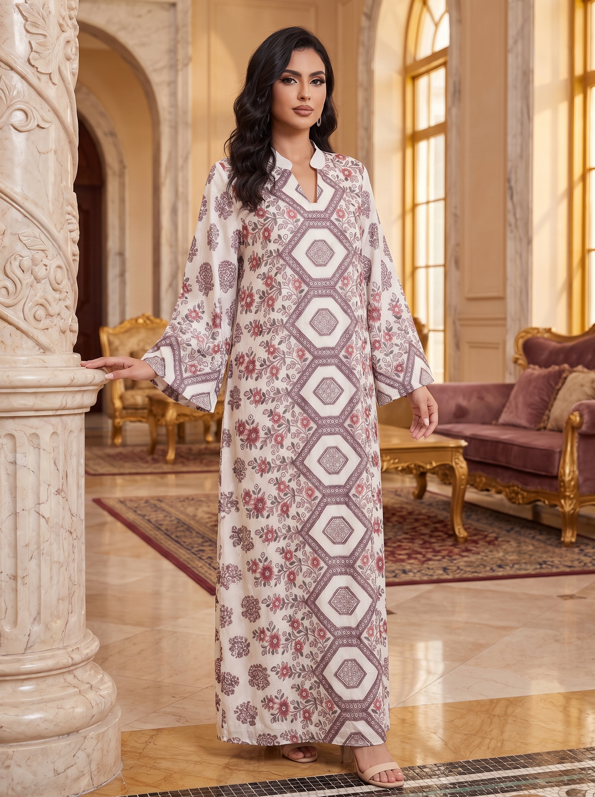 A woman modeling a long, loose-fitting kaftan dress with a geometric and floral print in beige, dusty pink, and brown, standing in an elegant, luxurious room with columns and gold-trimmed furniture.