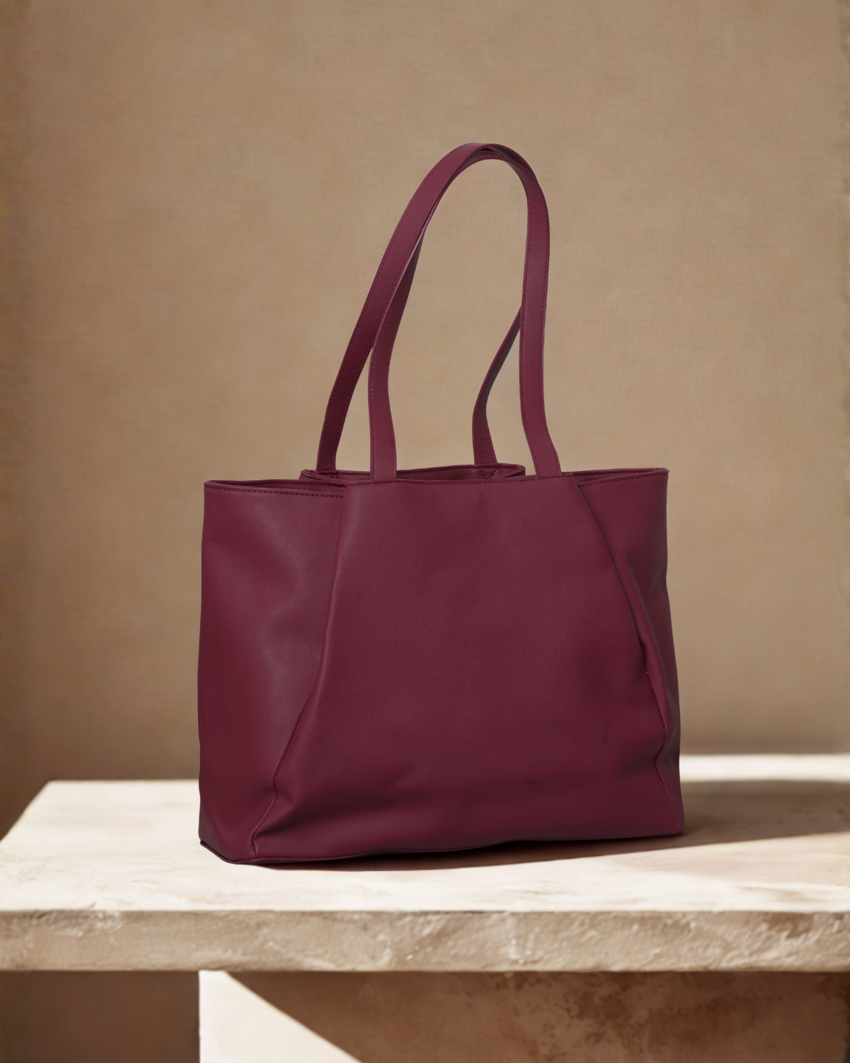 Maroon tote bag on a beige surface with a beige background